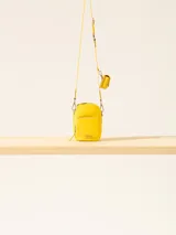 Bandolera amarilla con correa fina regulable y monedero colgante.