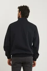 Campera estilo bomber color verde oscuro, con cierre metálico, dos bolsillos externos con cierre y un bolsillo interno.