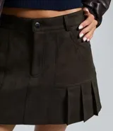 Short pollera de gamuza sintética color verde oliva, con diseño de tablas en el ruedo, cintura con trabillas y bolsillos delanteros.