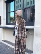 Blazer de corte sastrero con estampado de cuadros en tonos marrones y beige, con solapas clásicas y cierre frontal con botones.