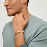 Pulsera de cuero marrón oscuro con abalorios en forma de gota bañados en plata y una pieza central dorada.