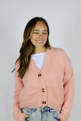Cardigan de punto color rosado, con escote en V, mangas largas y cierre frontal con tres botones carey.