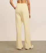 Pantalón deportivo recto color amarillo pastel, de media malla, con cintura elástica, bolsillos laterales y abertura en el ruedo.