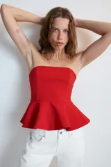 Top rojo sin tirantes, de escote recto y hombros descubiertos, con diseño ajustado en el torso y bajo acabado con peplum. Cierre lateral con cremallera oculta.