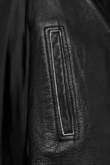 Chaqueta corta de piel 100% color negro, de estilo cruzado con cierre de hebilla lateral. Cuenta con cuello solapa ancho, manga larga con puños estructurados y forro interior.