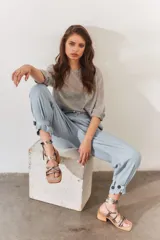 Sandalias de tacón bajo color bronce, con tiras finas cruzadas en el empeine y tiras largas para atar al tobillo. Tienen punta cuadrada y tacón de madera.