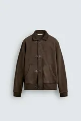 Chaqueta de algodón con interior de rizo, color marrón con efecto lavado. Presenta cuello de pana, bolsillos frontales tipo canguro, puños y ruedo en rib, y cierre frontal con alamares metálicos.