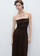 Vestido largo color marrón, con diseño palabra de honor y cuerpo entallado con detalle fruncido en la cintura. La falda presenta una caída fluida y amplia.