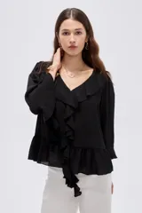 Blusa de poliéster color negro, con diseño holgado, escote en V con solapa y volados que descienden en cascada por el frente. Cuenta con mangas 3/4 con detalles de volados en los puños y en el ruedo.
