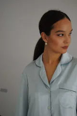 Pijama de satén elastizado color celeste, compuesto por una camisa de manga larga con cuello solapa, botones frontales y bolsillo en el pecho, y un pantalón recto con cintura elástica y lazo ajustable.
