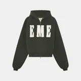 Campera con capucha y cierre frontal, color verde oscuro, con corte holgado (boxy fit). Presenta letras grandes en blanco con efecto desgastado en el pecho que dicen "EME".