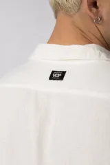 Camisa de manga larga con cuello clásico y cierre frontal de botones. Presenta un calce relajado y una textura liviana.