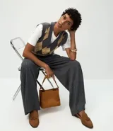 Chaleco de punto corto con diseño de rombos en tonos gris y beige. Presenta escote en V, sisas amplias y terminaciones acanaladas en el ruedo y el cuello.