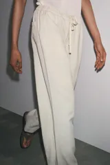 Pantalón jogger de la colección Zara Woman, color gris claro, confeccionado en hilatura con algodón y lyocell. Presenta tiro medio, cintura elástica ajustable con cordones, bolsillos laterales ocultos en costura y pierna ancha.