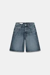 Bermuda baggy de denim azul con tiro medio, trabillas para cinturón y diseño de cinco bolsillos. Presenta cierre frontal con cremallera y botón metálico.