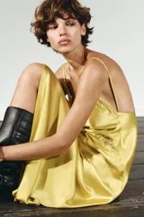 Vestido midi amarillo satinado con escote en pico, tirantes finos ajustables y detalle de encaje a tono en el escote y laterales.