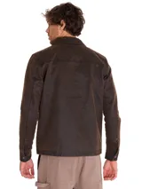 Chaqueta de estilo chore en tejido de sarga encerada color marrón, con cierre frontal metálico, cuello camisero y bolsillo con cierre en el pecho. Presenta un diseño de corte clásico con forro interno estampado.