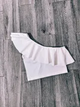 Top corto con un solo hombro y volado grande.