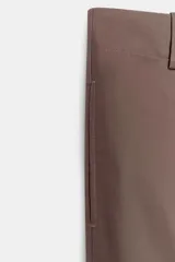 Pantalón marrón de tiro alto con bolsillos delanteros y traseros. El bajo está acabado con vuelta. Cierre frontal con cremallera y ganchos metálicos.