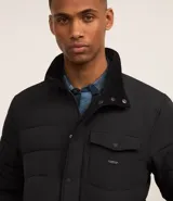 Campera puffer negra con cuello alto, cierre frontal con botones a presión, bolsillos laterales y un bolsillo cargo en el pecho. Presenta un diseño acolchado y forro interior suave.