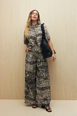 Conjunto de camisa y pantalón a rayas verticales en blanco y negro. La camisa es de manga corta, confeccionada en viscosa suave y fluida, con cuello clásico y botones al frente. El pantalón es de corte palazzo, con cintura alta y pernera ancha.