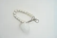Llavero de muñeca con cuentas perladas de efecto iridiscente, herrajes metálicos plateados y pompón de piel sintética blanca.