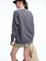 Cardigan de punto color marrón con textura jaspeada, escote en V, cierre frontal con botones y diseño de hombros caídos.