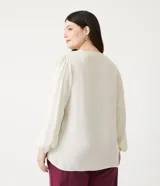 Blusa amplia color crema en viscosa con escote V con detalle de bordado en el escote, manga larga y elástico en el puño.