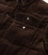 Campera puffer de Marfinno confeccionada en tejido de cotelé de algodón, con diseño acolchado, cuello inglés, cierre frontal con botones y dos bolsillos con solapa en el pecho.