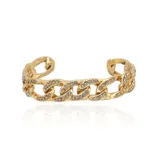 Brazalete rígido abierto con diseño de cadena de eslabones gruesos en tono dorado, adornado con incrustaciones de cristales brillantes en toda su superficie.