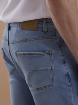 Jean azul piedra de corte recto, con diseño clásico de cinco bolsillos y cierre frontal de botón y cremallera.