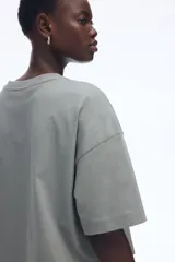 Remera gris de corte cuadrado y holgado, con cuello redondo y mangas cortas anchas. Confeccionada en tejido de punto suave de algodón.