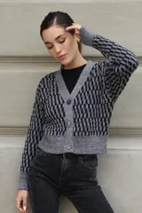 Cárdigan de tejido de punto con diseño geométrico en colores azul marino y plateado con lurex. Presenta escote en V, cierre frontal con botones, hombros caídos y largo medio.