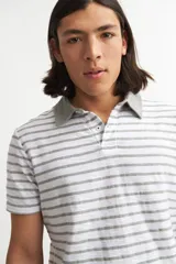 Remera de hombre a rayas horizontales blancas y grises, con cuello polo gris.