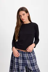 Remera de manga larga con cuello redondo, corte holgado y diseño básico en color negro.