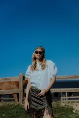 Minifalda color crema de cuero ovino con flecos y detalles en cuero marrón. Cierre frontal con cremallera. Estilo country.