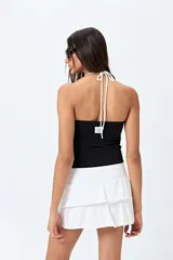 Top halter negro con escote en V y detalle de vivo blanco horizontal. Presenta un diseño ajustado al cuerpo y espalda descubierta con tiras regulables.
