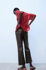 Pantalón de tiro medio confeccionado en 100% piel de color marrón, con diseño flare y costuras decorativas.