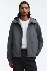 Campera rompevientos de nylon repelente al agua, con capucha ajustable, cierre frontal completo, bolsillos laterales y puños elásticos.