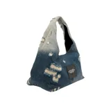 Bolso de hombro Marc Jacobs modelo The Sack Bag, confeccionado en denim azul con efecto desgastado y estampado del logo de la marca en blanco.