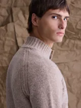 Sweater de punto en color beige, con cuello alto y cierre frontal parcial de botones. Presenta mangas largas con puños acanalados y diseño de corte clásico.