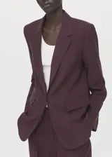 Blazer de diseño recto estilo traje, color bordó, confeccionado en tejido de lyocell. Cuenta con cuello pico con solapa de muesca, manga larga con puños abotonados, dos bolsillos laterales con solapa y cierre frontal de un botón.