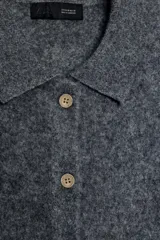 Chaqueta de punto con textura cepillada, cuello polo y manga corta. Presenta cierre frontal con botones y diseño de corte recto.