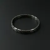 Pulsera de eslabones articulados de acero en tono gris oscuro con acabado mate.