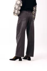 Jean de corte wide leg y tiro medio, confeccionado en denim de color gris oscuro con un lavado suave. Presenta una silueta recta y amplia, con cierre frontal y bolsillos laterales.