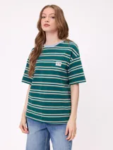Remera de corte holgado con diseño a rayas horizontales en tonos verde, blanco y marrón. Presenta cuello redondo en color gris claro, mangas cortas y un bolsillo frontal en el pecho con el logo de la marca estampado.