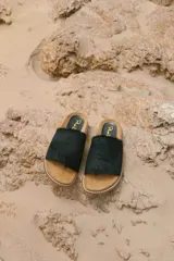 Sandalias de cuero negro con tira ancha de pelo y suela plana de corcho.