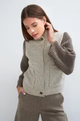 Campera de lana fina color crema, con cuerpo estructurado y mangas de tejido de punto acanalado. Presenta cuello alto, cierre frontal con botones y bolsillos laterales con doble abertura.