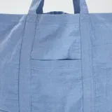 Bolso shopper de tela celeste con bolsillo frontal y asas de hombro.