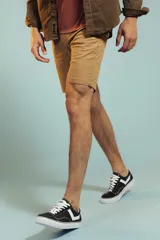 Bermuda de gabardina color tostado, de corte recto y largo por encima de la rodilla, con cierre y botón frontal.